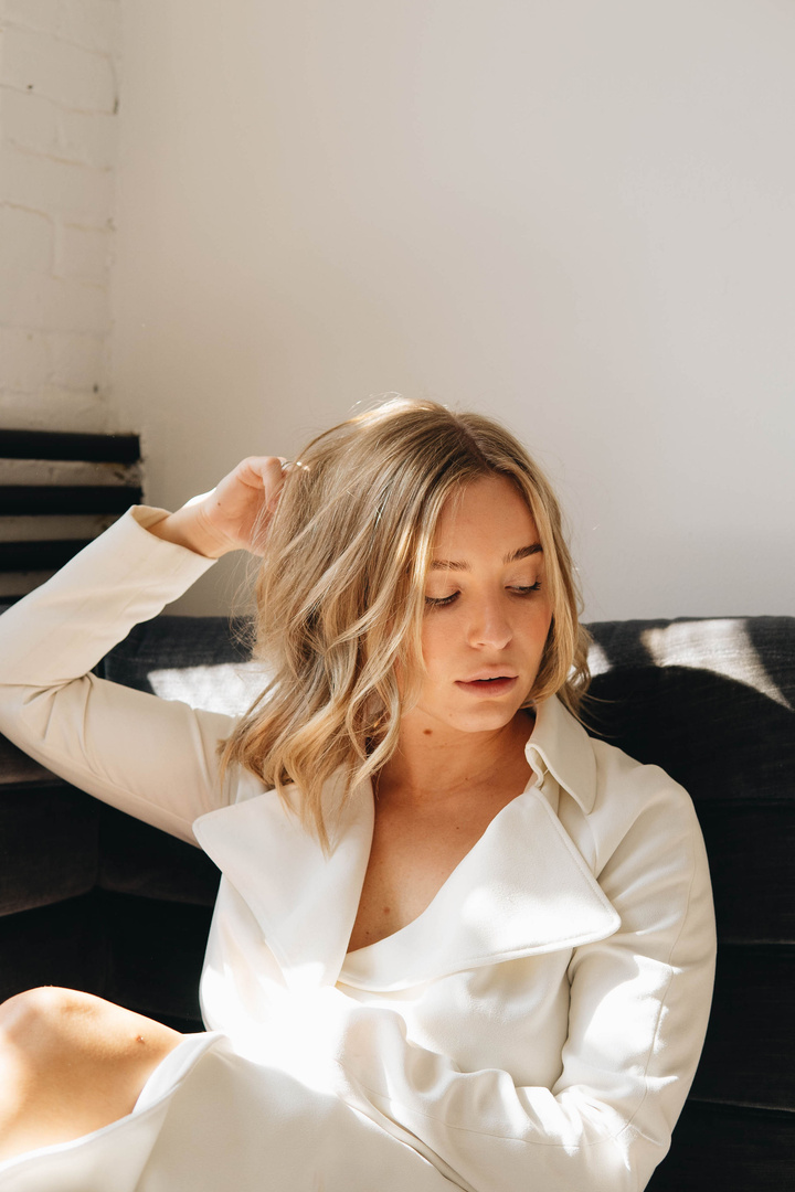 Woman in White Blazer Sitting on Black Sofa